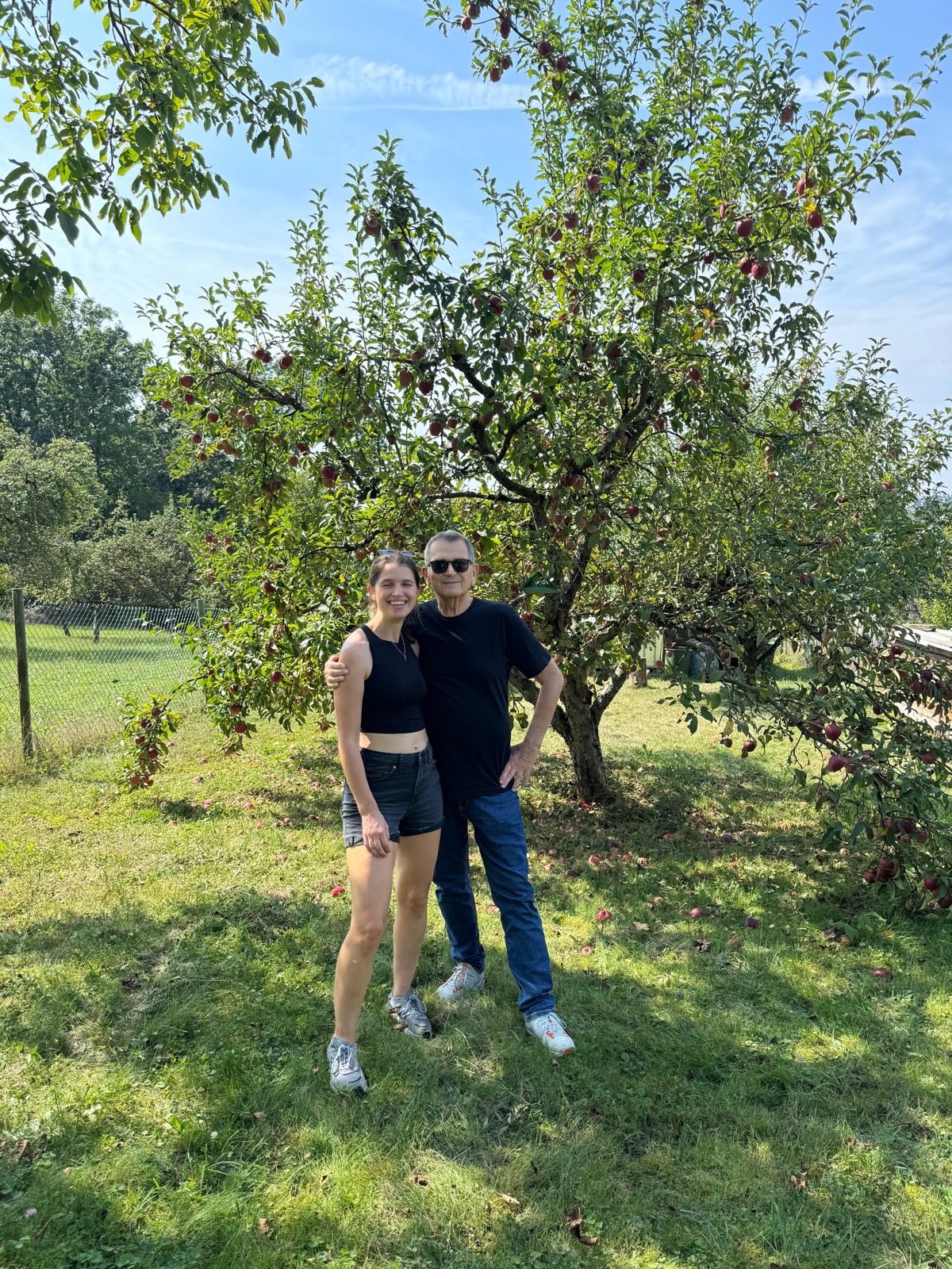 Carina und ihr Papa Walter unter einem Apfelbaum voller roter Äpfel