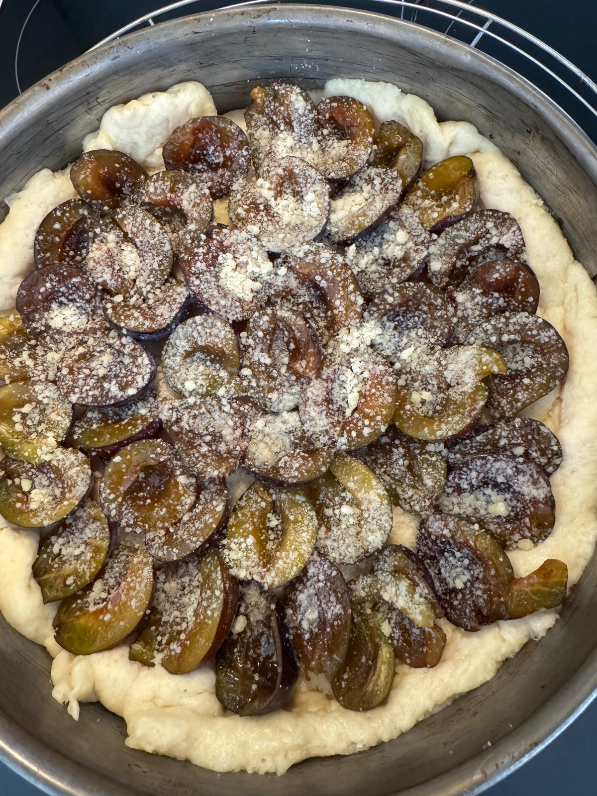 Runder Zwetschgenkuchen mit Streuseln vor dem Backen
